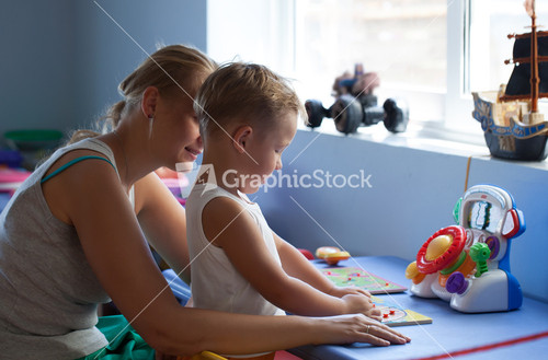 Mother watching little son playing learning game in his room